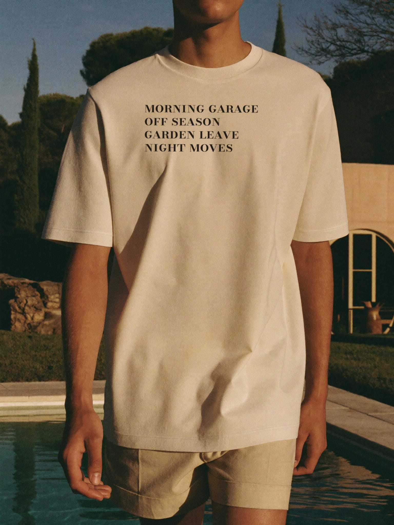 The List worn walking beside the villa pool — the four-line index printed high across the chest