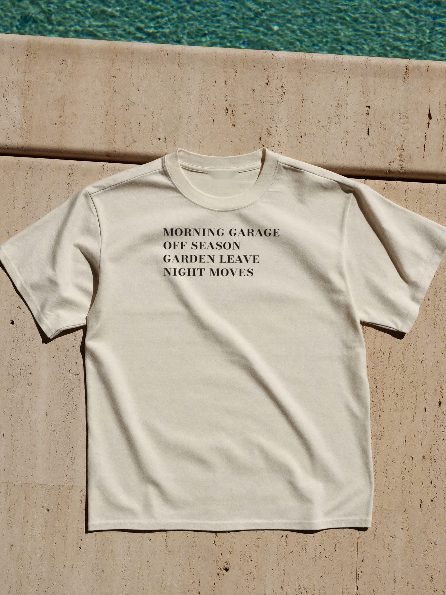 The garment laid flat on pool stone, the four-line index printed in a single ink across the chest.