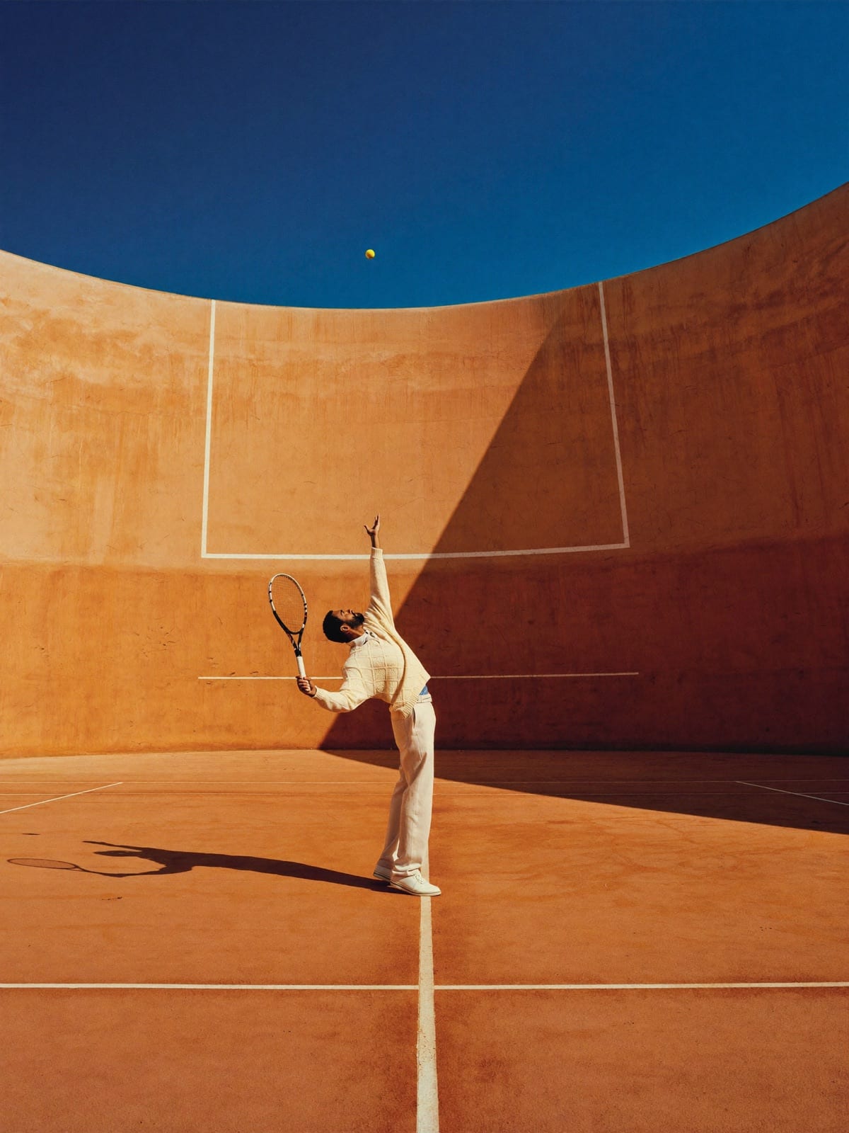 A server mid-toss inside an ochre amphitheatre of impossible scale.