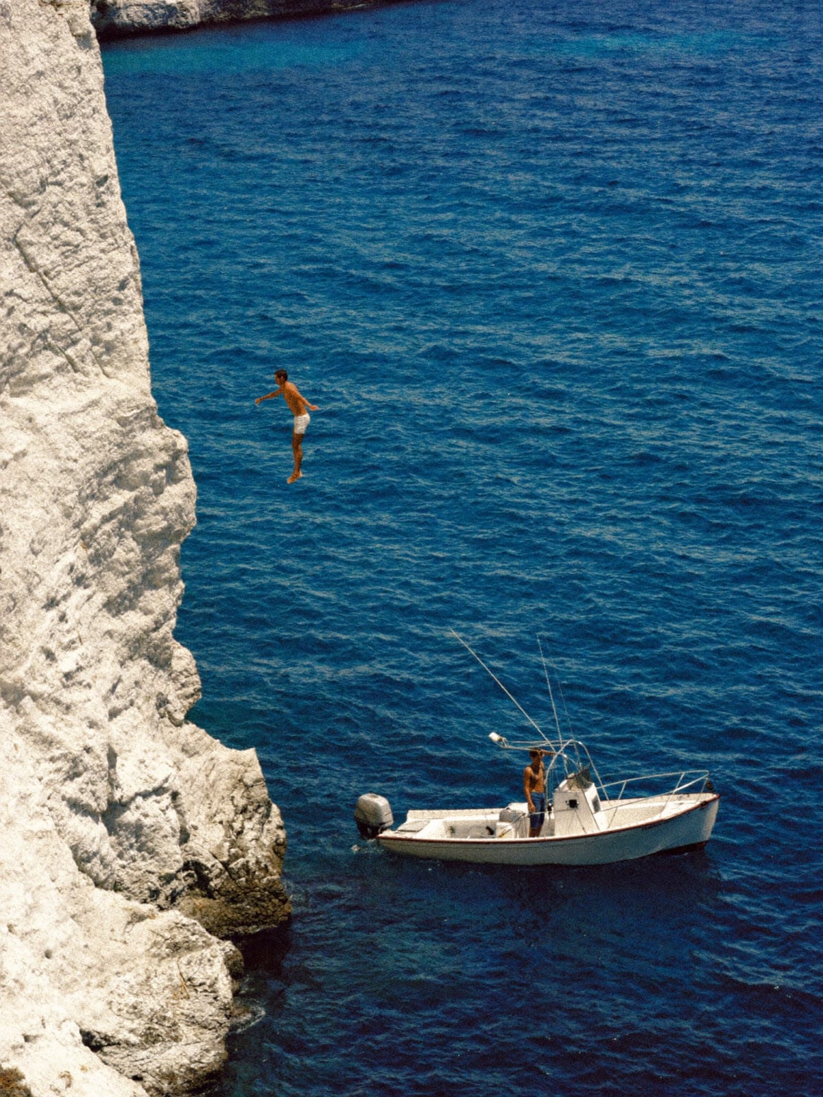 A figure suspended mid-dive above a dark pool, the surface unbroken beneath.